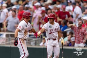 Arkansas Razorback infielder Brent Iredale (10) gets a fist bump from Logan Maxwell after scoring a run against the UCLA Bruins in the fifith inning during the College World Series on Tuesday, June 17, 2025 in Omaha, Nebraska. Photo by John S. Peterson.