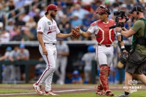 Arkansas Razorback catcher Ryder Helfrick (27) gives a fist bump to the pitcher Zach Root (33) after the first inning against the UCLA Bruins during the College World Series on Tuesday, June 17, 2025 in Omaha, Nebraska. Photo by John S. Peterson.