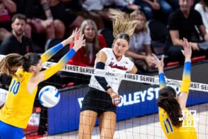 Nebraska Cornhusker Andi Jackson (15) spikes the ball against Pittsburgh Panthers Marina Pezelj (10) and Dalia Vîrlan (11) during the AVAC Showcase volleyball match on Friday, Aug. 22, 2025, in Lincoln, Nebraska. Photo by John S. Peterson.