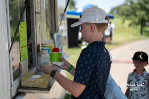 A young fan buying a snow cone during The Pinnacle Bank Championship on August 8th, 2025, in Omaha, Nebraska. Photo by Brandon Tiedemann.