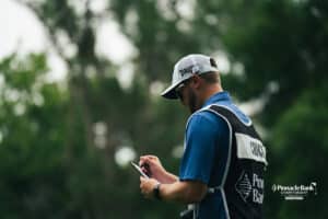Brandon Crick's caddy writes notes during the Pinnacle Bank Championship golf tournament Thursday, August 7th, 2025, in Omaha, Nebraska. Photo by Nick Barajas.