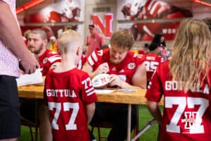 Nebraska Cornhusker Gunnar Gottula (77) signs an autograph for couple young fans with his jersey number during Nebraska’s football Fan Day on Saturday, Aug. 2, 2025 in Lincoln, Nebraska. Photo by John S. Peterson.