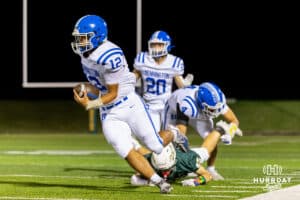 Bennington quarterback Ty Buaphakeo (12) evades a fallen Gretna defender to move further upfield during a High School Football game, Friday, September 26th, 2025, Gretna, Nebraska. Photo by Braden Cochran.
