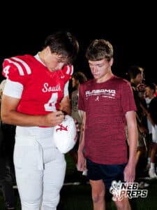Jett Thomalla signs a football after the Millard South football game vs Lincoln Southeast on September 25th, 2025 in Omaha, Nebraska. Photo by Drew Balus