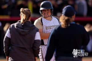 A Northwest batter talks with her coach after making it to first base during a high school softball championship game, Monday, October 20, 2025, Lincoln, Nebraska. Photo by Braden Cochran.
