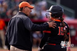 A Beatrice coach talks with batter Jada Berke (15) after making it to first base during a high school softball championship game, Monday, October 20, 2025, Lincoln, Nebraska. Photo by Braden Cochran.