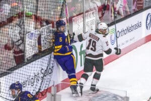 Omaha Maverick Sean Tschigerl (19) pushes Minnesota State Maverick Mason Wheeler (5) into the student section's line up of signs during a college hockey game against Minnesota State on Friday, October 10, 2025, in Omaha, Nebraska. Photo by Dawson Anderson.