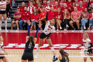 Volleyball player spikes ball over net.