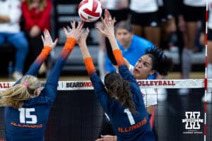 Nebraska Cornhusker outside hitter Teraya Sigler (11) spikes the ball over Illinois Fighting Illini middle blocker Gabby Dean (15) and opposite Auburn Tomkinson (1) in the third set during a college volleyball match on Thursday, November 6, 2025, in Lincoln, Nebraska. Photo by John S. Peterson.