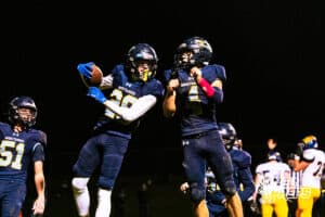 Concordia's Parker Olson (28) and Drew Kulus (4) are celebrating after scoring a touchdown during a high school football game against Wahoo on Friday, October 24, 2025 in Omaha, Nebraska. Photo By Jack Stephens.