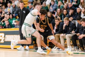 Gretna East point guard Drayke Brown (32) passes the ball behind his back to move past a defender during a high school basketball game Thursday, December 11, 2025, in Lincoln, Nebraska. Photo by Braden Cochran.