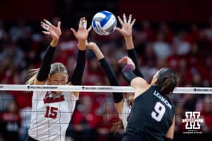 Texas A&M Aggie opposite Logan Lednicky (9) spikes the ball against Nebraska Cornhusker middle blocker Andi Jackson (15) and outside hitter Harper Murray (27) in the second set during the NCAA Volleyball Regional on Sunday, Dec. 14, 2025, in Lincoln, Nebraska. Photo by John S. Peterson.