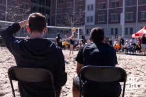 Nebraska Cornhusker Keri Leimbach (6) hits the ball over the net as head coach Jaylen Reyes, right, and Brennan Hagar watch against Wayne State Wildcats during a beach volleyball match on Friday, Feb. 27, 2026, in Lincoln, Nebraska. Photo by John S. Peterson.