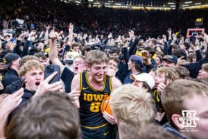 Iowa Hawkeye forward Cooper Koch (8) surrounded by Iowa students storming the court after the win over the Nebraska Cornhuskers during a college basketball game on Tuesday, Feb. 17, 2026, in Iowa City, Iowa. Photo by John S. Peterson.