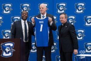 Creighton Bluejay head coach in waiting Alan Huss holds up his jersey during his introductory press conference on March 25, 2026, in Omaha, Nebraska. Photo by Brandon Tiedemann