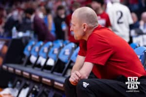 Nebraska Cornhusker assistant coach Nate Loesner takes a seat watching the celebration after the win over the Troy Trojans for the first Nebraska win during the first round of the NCAA Men’s Basketball Championship on Thursday, March 19, 2026, in Oklahoma City. Photo by John S. Peterson.