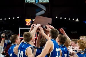 Archangel Catholic boys basketball players reach for their first-place trophy during a boys state final basketball game, Mar. 14, 2026, Lincoln, Nebraska. Photo by Braden Cochran.