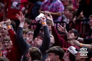 Nebraska Cornhusker fans reach to catch a t-shirt from a t-shirt toss at a break in the action against the Iowa Hawkeyes during a college basketball game on Sunday, March 8, 2026, in Lincoln, Nebraska. Photo by John S. Peterson.