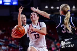 Norris’ Kallen Stauffer (13) is laying the ball up through two Blair defenders during a high school basketball game against Blair in the first round of the NSAA state girls basketball tournament on March 4, 2026 in Lincoln, Nebraska. Photo By Jack Stephens.