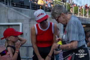 Omaha Softball legend Connie Claussen signs a softball during a college softball game against Nebraska on April 21, 2026, in Omaha, Nebraska. Photo by Brandon Tiedemann