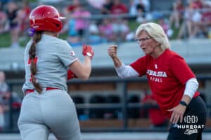 Nebraska Cornhusker Ava Kuszak (7) fist bumps head coach Rhonda Revelle during a college softball game against Omaha on April 21, 2026, in Omaha, Nebraska. Photo by Brandon Tiedemann