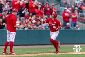 Nebraska Cornhusker Drew Grego (10) celebrates his home run with the third base coach, Lance Harvell, against the Southern California Trojans during a college baseball game on Saturday, April 18, 2026, in Lincoln, Neb. Photo by John S. Peterson.