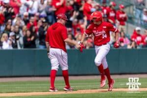 Nebraska Cornhusker infielder Case Sanderson (14) gives third base coach Lance Harvell a fist bump running the bases after hitting a home run in the third inning against the Southern California Trojans during a college baseball game on Saturday, April 18, 2026, in Lincoln, Neb. Photo by John S. Peterson.