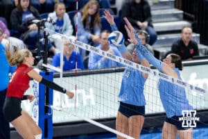 Creighton Bluejay setter Rayna Christianson (4) and Eloise Brandewie block a spike from Nebraska Cornhusker outside hitter Gabby DiVita (23) in the fourth set during a college volleyball match on Friday, April 17, 2026, in Omaha, Neb. Photo by John S. Peterson.