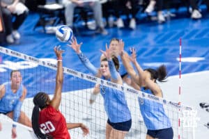 Creighton Bluejay middle blockers Ayden Ames (5) and Destiny Ndam-Simpson jump to block Nebraska Cornhusker outside hitter Jayden Robinson (20) in the fourth set during a college volleyball match on Friday, April 17, 2026, in Omaha, Neb. Photo by John S. Peterson.
