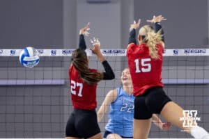Creighton Bluejay right side hitter Ashlyn Paymal (22) spikes the ball past Nebraska Cornhuskers Harper Murray (27) and Andi Jackson (15) during a college volleyball match on Friday, April 17, 2026, in Omaha, Neb. Photo by John S. Peterson.