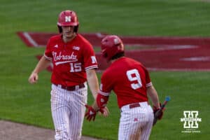 Nebraska Cornhusker Dylan Carey (15) gives Rhett Stokes five after scoring a run against the Creighton Bluejays in the third inning during a college baseball game on Tuesday, April 14, 2026, in Lincoln, Neb. Photo by John S. Peterson.