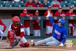 Kansas Jayhawk Josh Dykhoff (16) scores a run against Nebraska Cornhusker catcher Jeter Worthley (0) in the fifth inning during a college baseball game on Tuesday, April 7, 2026, in Lincoln. Photo by John S. Peterson.