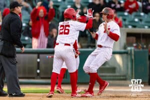Nebraska Cornhusker Miken Miller (26) and Josh Overbeek celebrate scoring runs in the second inning against the Kansas Jayhawks during a college baseball game on Tuesday, April 7, 2026, in Lincoln. Photo by John S. Peterson.