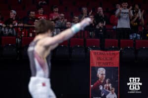 Nebraska Cornhusker Asher Cohen celebbrates his performance on the still rings with Jim Hartung banner in the background during the Big Ten Men’s Gymnastics Championships on Saturday, April 4, 2026, in Lincoln. Photo by John S. Peterson.