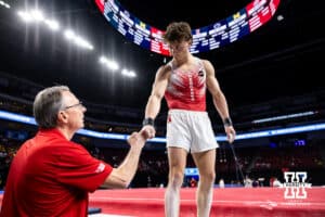 Nebraska Cornhusker Chase Mondi and head coach Chuck Chmelka fist bump before his floor performance during the Big Ten Men's Gymnastics Team Championship on Friday, April 3, 2026, in Lincoln. Photo by John S. Peterson.