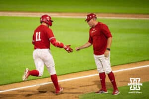 Nebraska Cornhusker Max Buettenback (11) high fives his coach during a regional baseball game against Ole Miss on May 30, 2026, in Lincoln, Nebraska. Photo by Brandon Tiedemann.
