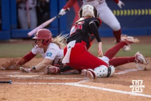 Nebraska Cornhusker catcher Jesse Farrell (25) tags out Alabama Crimson Tide Ambrey Taylor (36) out at home plate in the second inning during the WCWS second round on Saturday, May 30, 2026, in Oklahoma City. Photo by John S. Peterson.