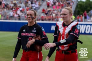 Nebraska Cornhuskers starting pitcher Jordyn Frahm (98) and catcher Jesse Farrell (25) walk to the dugout after warming up during the WCWS second round on Saturday, May 30, 2026, in Oklahoma City. Photo by John S. Peterson.