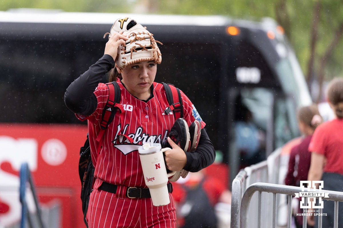 Nebraska Cornhusker Bella Bacon (3) arrives at the stadium with her glove on her head to protect her from the rain during the WCWS softball media day on Wednesday, May 27, 2026, in Oklahoma City. Photo by John S. Peterson.