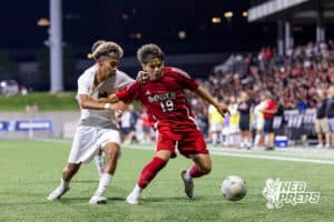 Omaha South’s Erick Perlera (19) is dribbling the ball through heavy contact from Omaha Westside’s Sebastian Perez Rojas (20) during semi-finals of the NSAA State Soccer Championships on Friday, May 15, 2026, in Omaha, Nebraska. Photo By Jack Stephens.