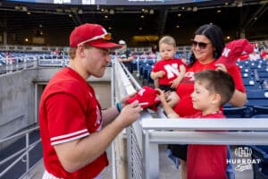 Nebraska Cornhusker Josh Overbeek (4) signs an autograph for a young fan before taking on the Creighton Bluejays during a college baseball game on Tuesday, May 12, 2026, in Omaha, Neb. Photo by John S. Peterson.
