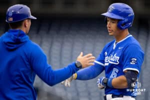 Creighton Bluejay Isaac Wachsmann (6) high fives his first base coach after being walked during a college baseball game against the Kansas Jayhawks on Tuesday, May 5, 2026, in Omaha, Nebraska. Photo by Braden Cochran.