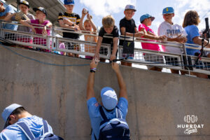 North Carolina Tar Heel signs a baseball for a young fan during the CWS media day on Thursday, June 11, 2026, in Omaha, Neb. Photo by John S. Peterson.