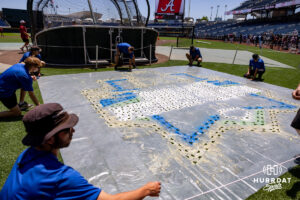 Grounds crew start the process of paing the CWS logo behind home plate during the CWS media day on Thursday, June 11, 2026, in Omaha, Neb. Photo by John S. Peterson.