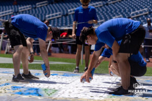 Grounds crew start the process of paing the CWS logo behind home plate during the CWS media day on Thursday, June 11, 2026, in Omaha, Neb. Photo by John S. Peterson.