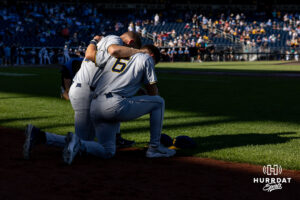 West Virginia Mountaineer Brayden Robinson (33) and Paul Schoenfeld (6) grab a knee for a preayer before taking on the North Carolina Tar Heels during the College World Series baseball tournament on Sunday, June 14, 2026, in Omaha, Neb. Photo by John S. Peterson.