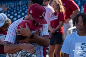 Alabamas Justin Lebron (1) hugs family during a CWS game on June 15, 2026, in Omaha, Nebraska. Photo by Brandon Tiedemann.