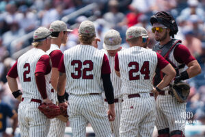 The Troy Trojans meet on the mound during a CWS game on June 16, 2026, in Omaha, Nebraska. Photo by Brandon Tiedemann.