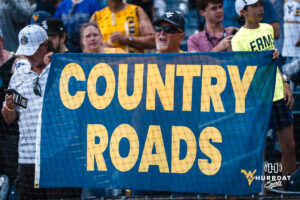 A West Virginia Mountaineers fan holds up a Country Roads sign after a CWS game on June 16, 2026, in Omaha, Nebraska. Photo by Brandon Tiedemann.