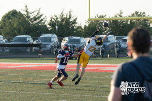 Two boys football players compete during a game on an outdoor field.